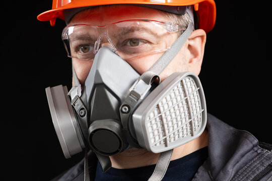 A man wearing a helmet, respirator and goggles on a black background - Powered by Adobe