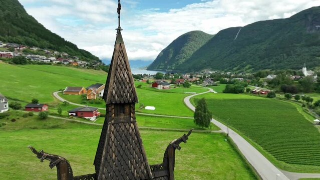 Top of Hopperstad Stave Church Tower in Vik Sogn Norway - Aerial orbit with parallax and fjord view in background