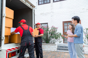 Asian couple sign delivery logistic form, checking cardboard box belonging using logistic business service, Multiethnic house moving employees in uniform work professional teamwork in moving company