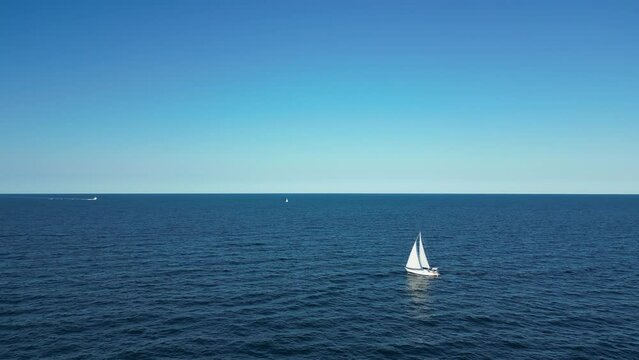 aerial view from the drone of a sailboat plying the slightly choppy blue sea off the coast of Rimini Italy