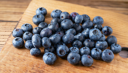 Blueberries on a board over wooden table.