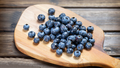 Blueberries on a board over wooden table.