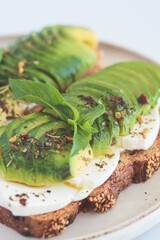 Breakfast toast with cream cheese and avocado on white plate, white background. Healthy food concept.
