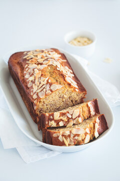 Banana bread with almonds on a white plate on white background.