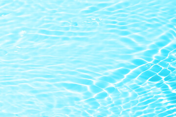 Blue water with ripples on the surface. Defocus blurred transparent blue colored clear calm water surface texture with splashes and bubbles. Water waves with shining pattern texture background.
