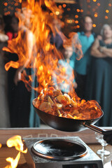 A frying pan with fire at a cooking show in a restaurant for people