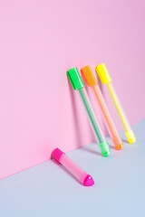 Creative background of bright stationery markers, text highlighters, felt-tip pens on a gray-pink background, selective focus