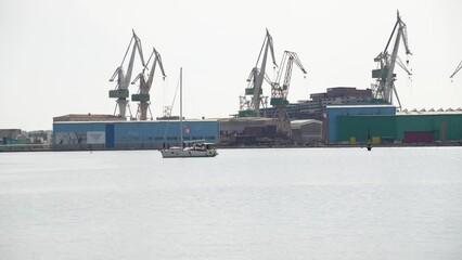 A white Yacht with red flag and crew leaves Pula harbour in Croatia - Powered by Adobe
