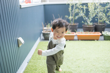春の昼間の自宅の庭の芝生の上で笑顔で走り出す瞬間の日本人の少年