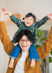 秋の日中の家のリビングで肩車して2人で笑顔で遊ぶアジア人の父子