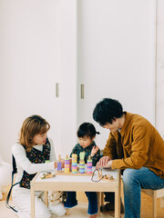 春の昼下がり、子ども部屋で座って3人でおもちゃで遊ぶ日本人の家族