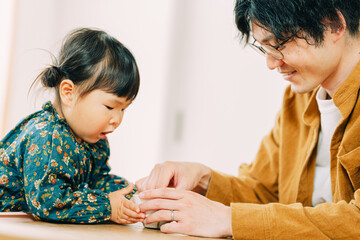 冬の昼、室内でお菓子をつまむ日本人の男性と見守る小さな子ども