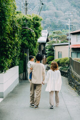 春の夕方、道で娘を抱っこして歩く仲の良い日本人の家族の後ろ姿