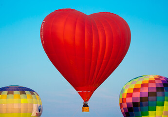 Love Balloon in the shape of a heart against the blue sky in flight, colorful cheerful entertaining...