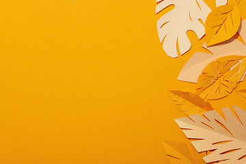 Paper yellow tropical leaves on a yellow background.