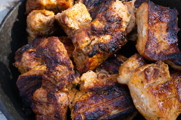 BBQ. roasted on a barbeque beef, pork pieces. Bright brown grilled meat with crust lie in pan on open air. Fast food concept. Unhealthy food , fat and calories. Top view 