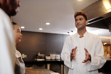 Fototapeta na wymiar Excited restaurant chef talking to sous-chefs, discussing new menu