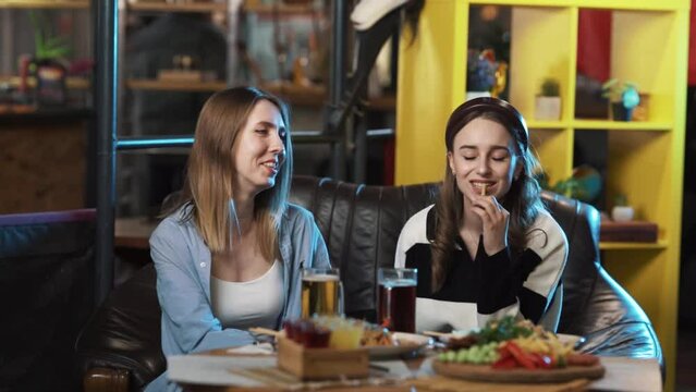 Young girls are sitting in a restaurant with lots of food on the table. They are in good spirits, chatting and eating happily. They are talking very emotionally.