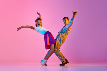 Talented, artisitc children, boy and girl in retro clothes dancing lindy hop against pink studio...