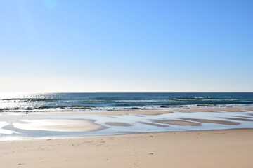 Deserted natural beach with sun reflections, calm blue sea, cloudless blue sky and clear horizon,...