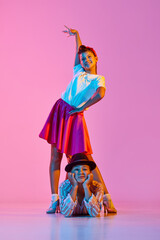 Emotive, stylish children,. boy and girl in beautiful clothes dancing retro dance against pink...
