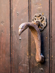 Antique door knocker on a wooden door in a medieval village in Provence