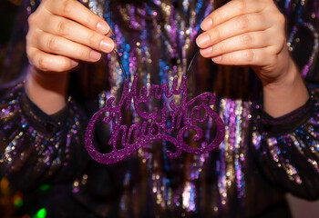 Woman hand holds a lilac inscription Merry Christmas....