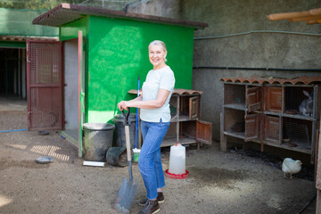 A woman stands in front of cages with rabbits.