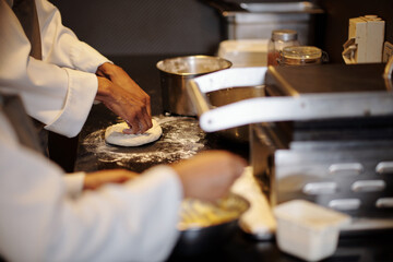 Hands of cook kneading piece of dough when making small pizzas