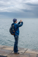 Port-en-Bessin-Huppain, France - 07 24 2023: A woman takes photo of the sea and cliffs from the...