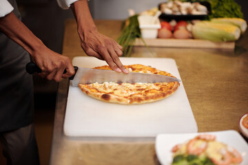 Pizzamaker using big sharp knife when cutting small pizza in slices