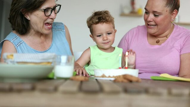 grandmother mom and little boy with birthday cake blowing out candles, happy birthday