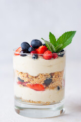 Cold dessert in a glasses with berries, mint, nuts, whipped cream and biscuit. Healthy food, vegan, sugar, gluten and lactose free.