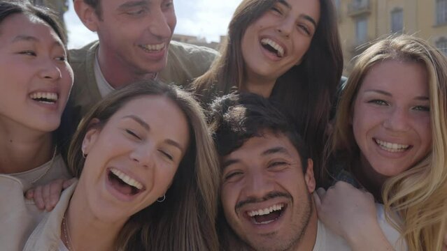 Mobile selfie of group young multi-ethnic beautiful friends having fun together outdoors. Excited people looking at happy camera enjoying sightseeing in city on sunny day. Generation z and vacations.