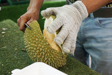 A man cuts open a durian at a fruit stall.