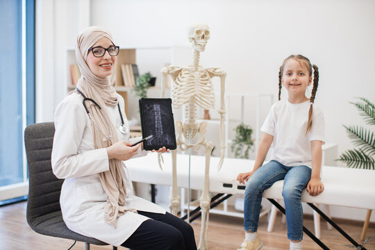 GP with CT scans on tablet and girl posing at doctor's
