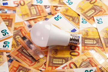 Energy saving light bulb and european money. Conceptual view