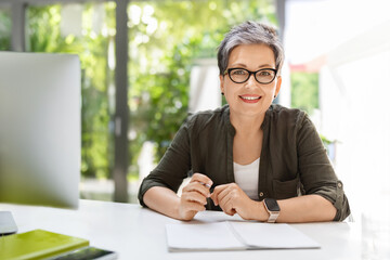 Cheerful mature woman business consultant working at office