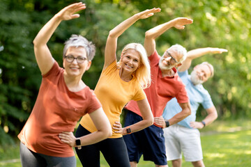 Group of sporty mature people doing stretching exercises at park