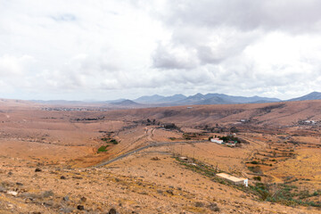 Desertic landscape of the interior of Fuerteventura island. Rocky hills with white sand. Sky with big white clouds. Sunny day Fuerteventura, Canary Islands, Spain.