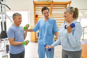 Therapist assisting elderly patients exercising with dumbbells