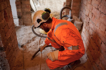 Close up of constriction site worker cleaning concrete floor with vacuum cleaner after demolishing...