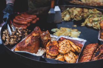 Food festival with food stall kiosk, open-air outdoor fair market, assortment of different traditional European grilled barbecued street food with sausages, bbq, chicken, pork and lamb on a large pan