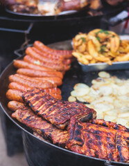Food festival with food stall kiosk, open-air outdoor fair market, assortment of different traditional European grilled barbecued street food with sausages, bbq, chicken, pork and lamb on a large pan
