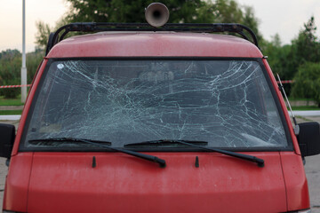 Red car with broken windscreen after crash on road or traffic accident, close up
