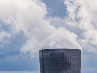 View of the steam coming out of the chimney in a nuclear power plant. Blue sky in the background
