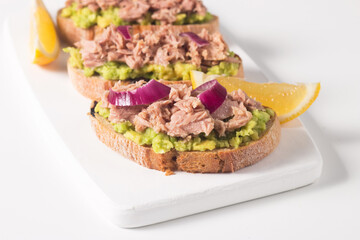 Toast with Canned Tuna. Fish open sandwich with avocado, red onion and lemon. 