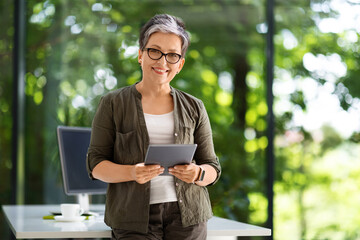 Cheerful middle aged businesswoman using digital tablet at office