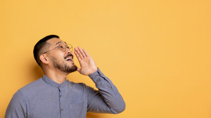 Excited Young Asian Man With Hand Near Mouth Making Announcement