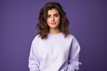 Fototapeta premium Young woman showcasing blank white sweatshirt against purple background